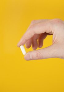 person holding white vitamin