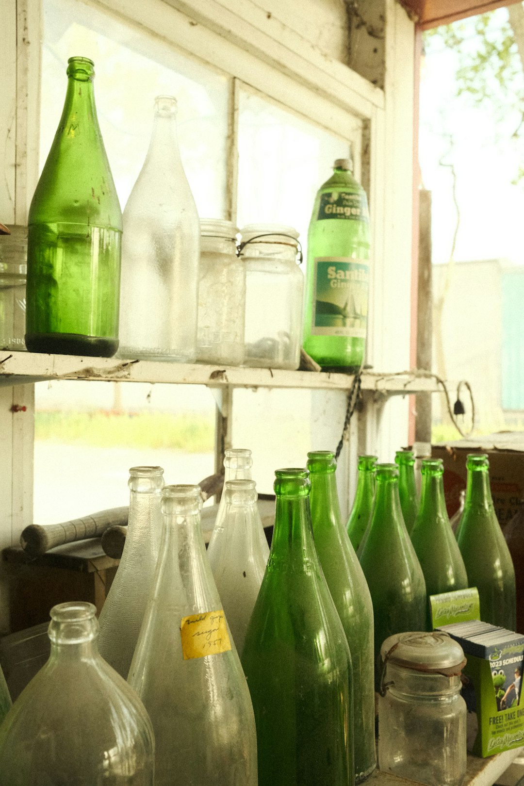 a shelf filled with lots of green glass bottles